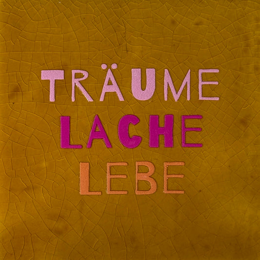 Quote tegeltje 'träume lache lebe' oker/warmroze(knalroze-oranje)